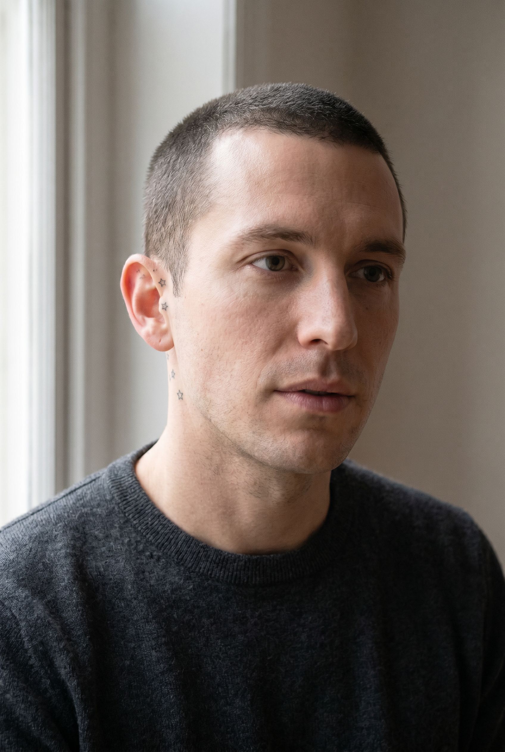Petites étoiles minimalistes tatouées derrière l'oreille d'un homme