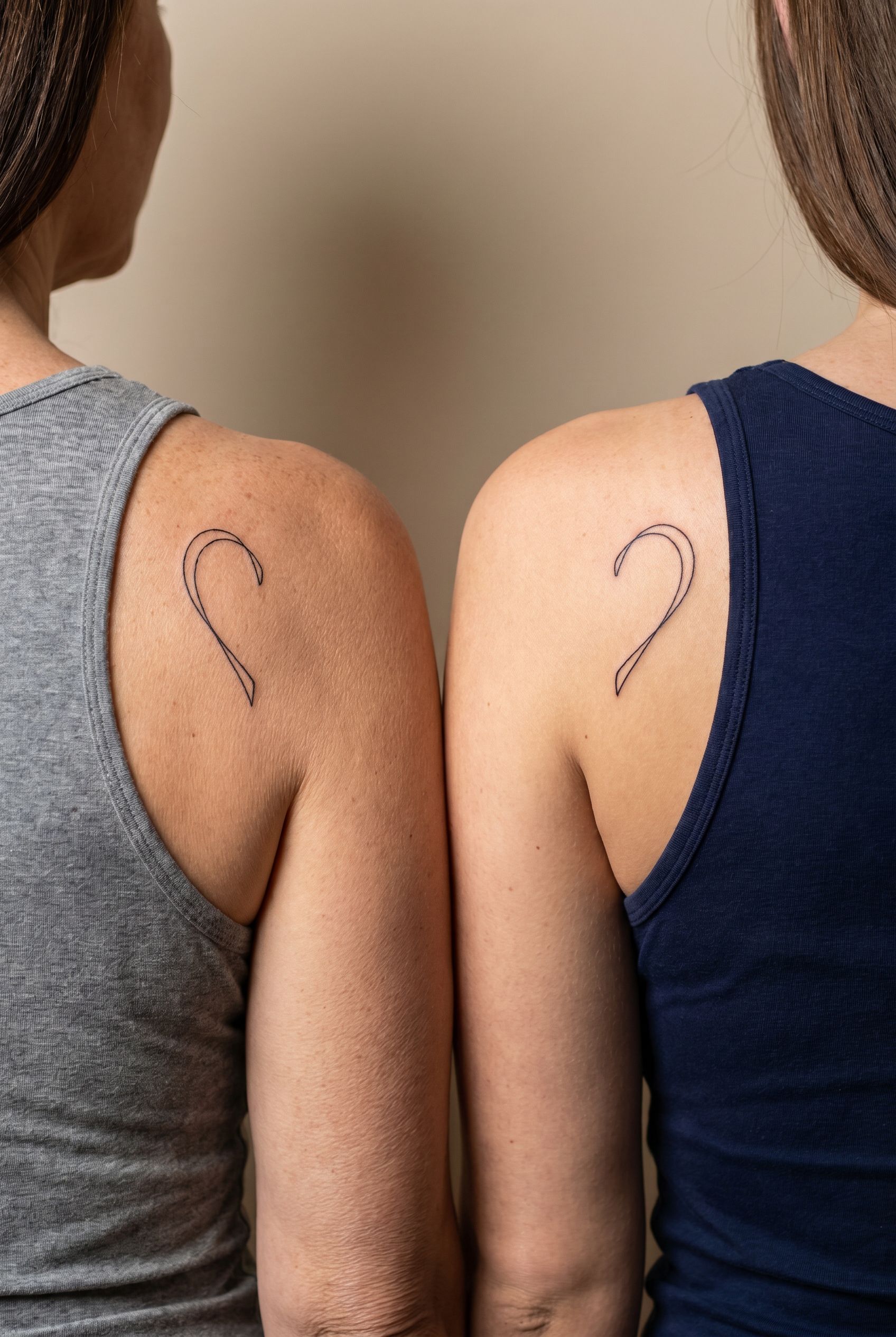 Tatouage d'un cœur coupé en deux moitiés complémentaires sur l'omoplate d'une mère et de sa fille