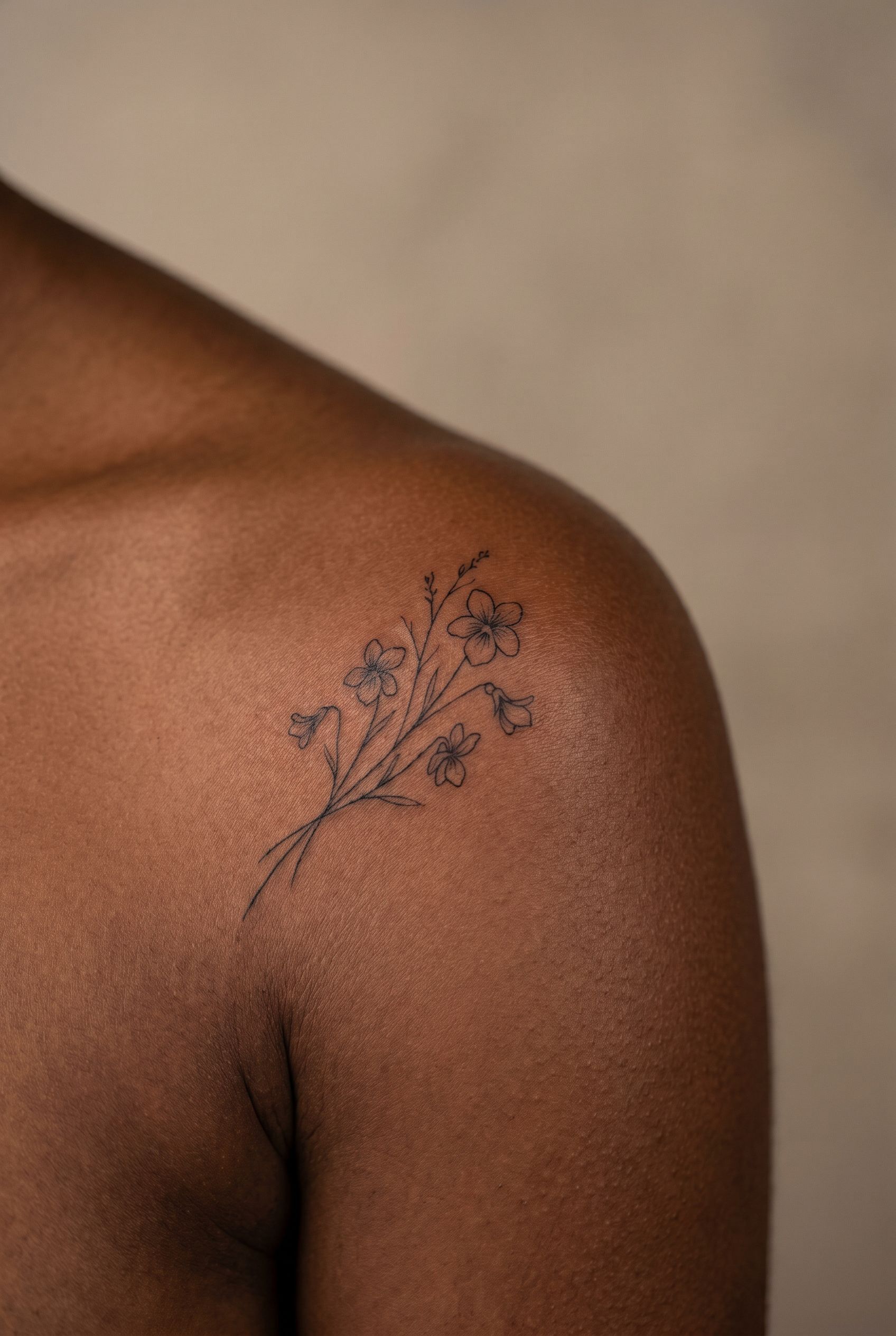 Petites fleurs assorties en fine line tatouées sur l'épaule d'une femme
