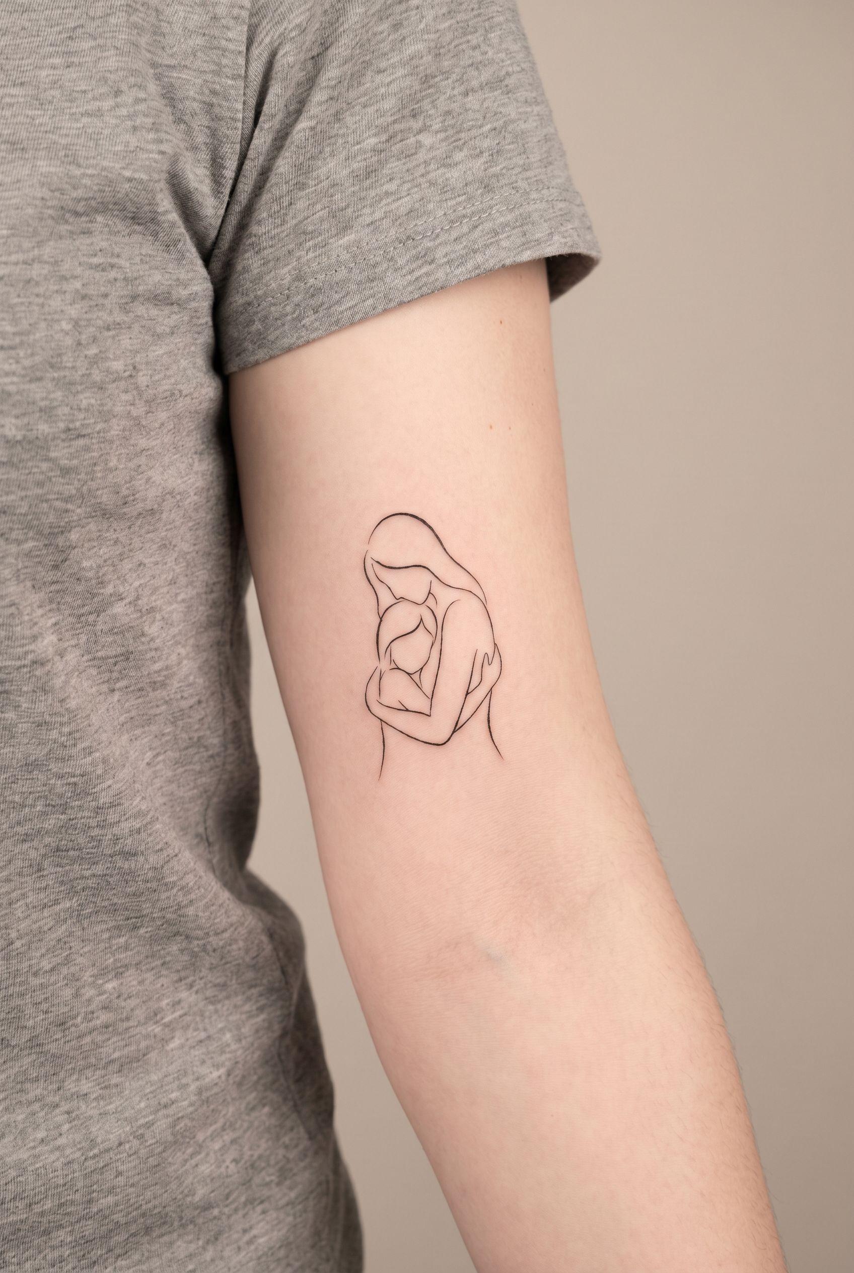 Tatouage épuré de deux silhouettes enlacées sur l'avant-bras d'une femme
