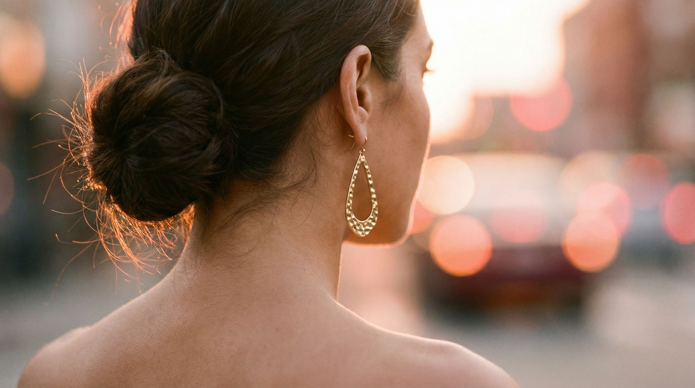 Chignon et boucles d'oreilles sculpturales, l'élégance de la nuque dégagée
